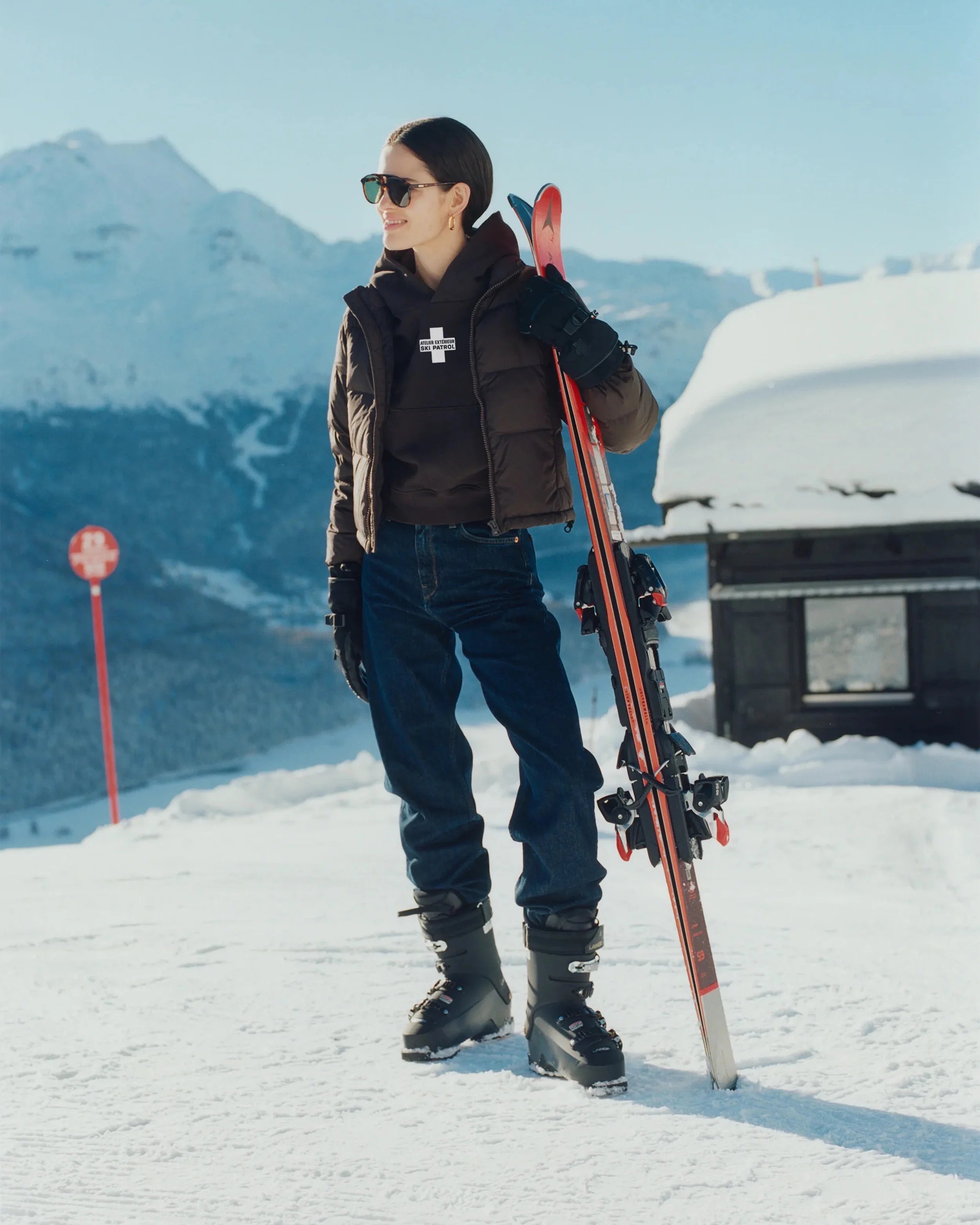 Person holding skis on a snowy mountain with a mountainous background