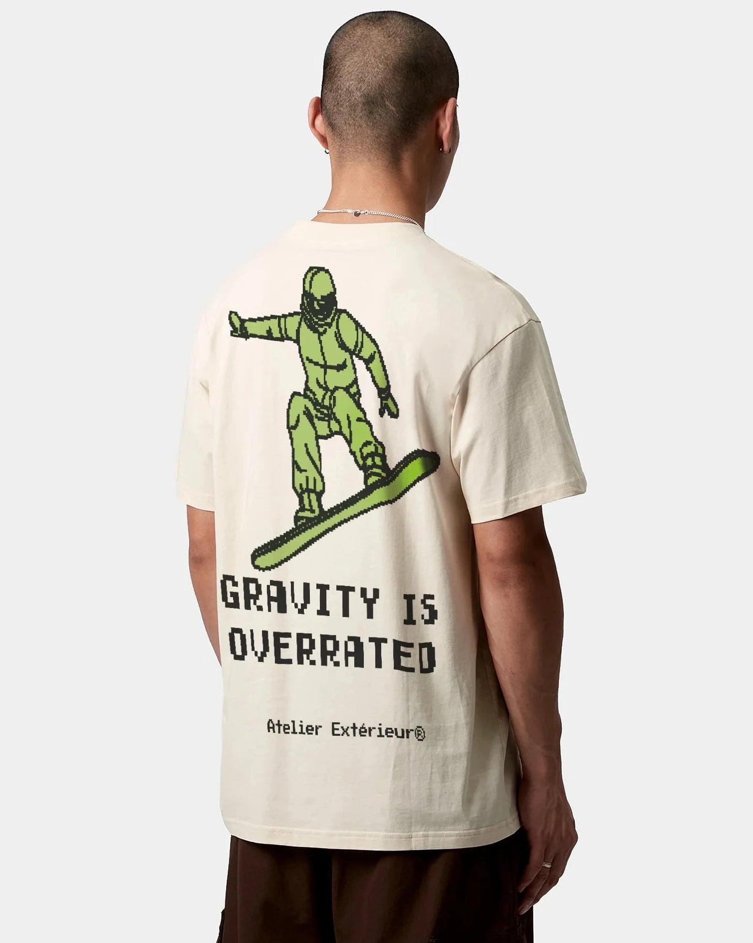 A person wearing an oversized white t-shirt with a graphic print of a snowboarder and the text 'GRAVITY IS OVERRATED'.