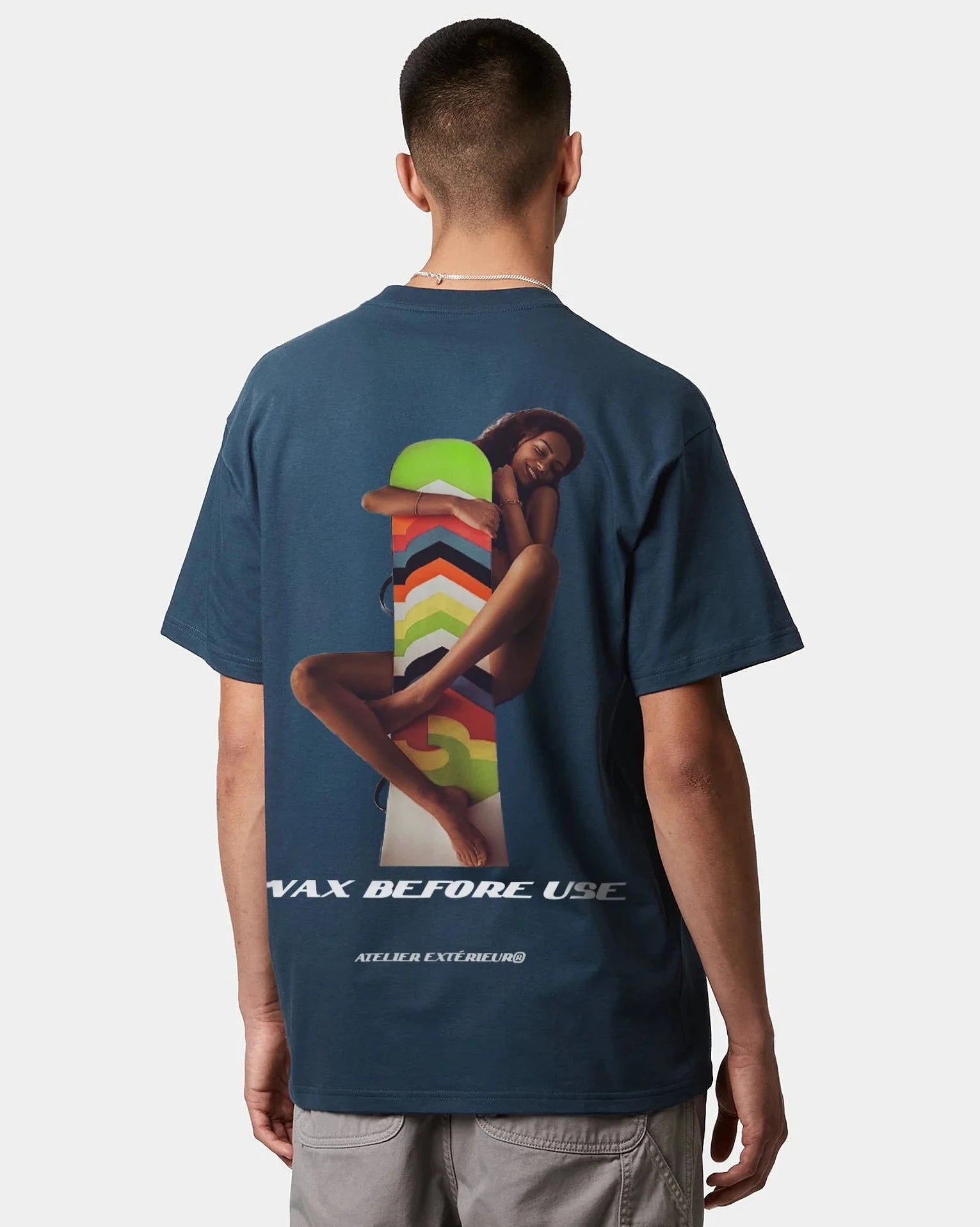 A person wearing a blue oversized tee with text and graphic artwork on the front.