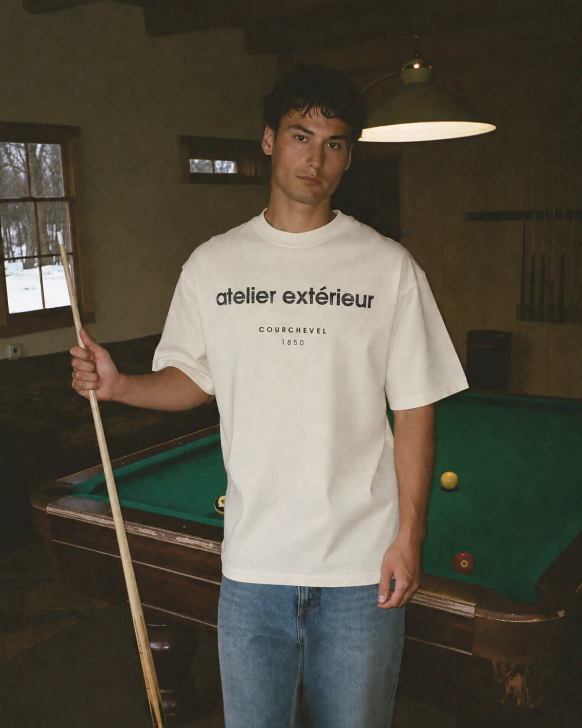 Man wearing the ecru Courchevel 1850 ski tee in an après-ski games room