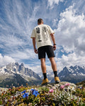 Person standing on a mountain top with a scenic view of mountains and blue sky.