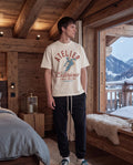 Person standing in a wooden cabin with a scenic view of mountains.