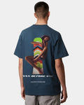 A person wearing a blue oversized tee with text and graphic artwork on the front.