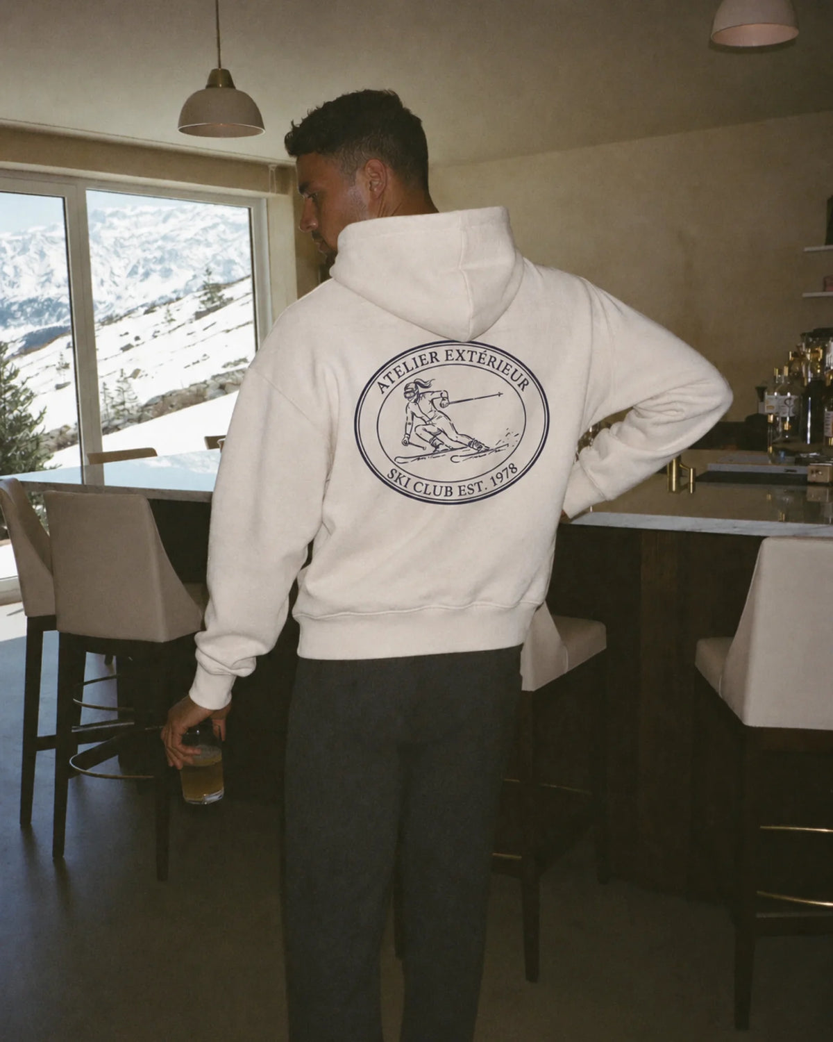 Man wearing the Alpine Ski Club Hoodie in ecru, on location