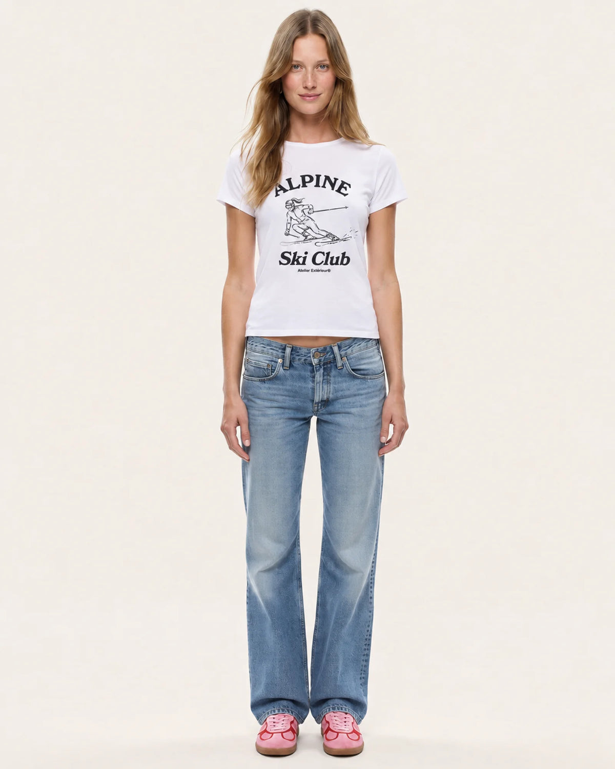 Model wearing the Alpine Ski Club women's tee in white with straight-leg jeans, front view