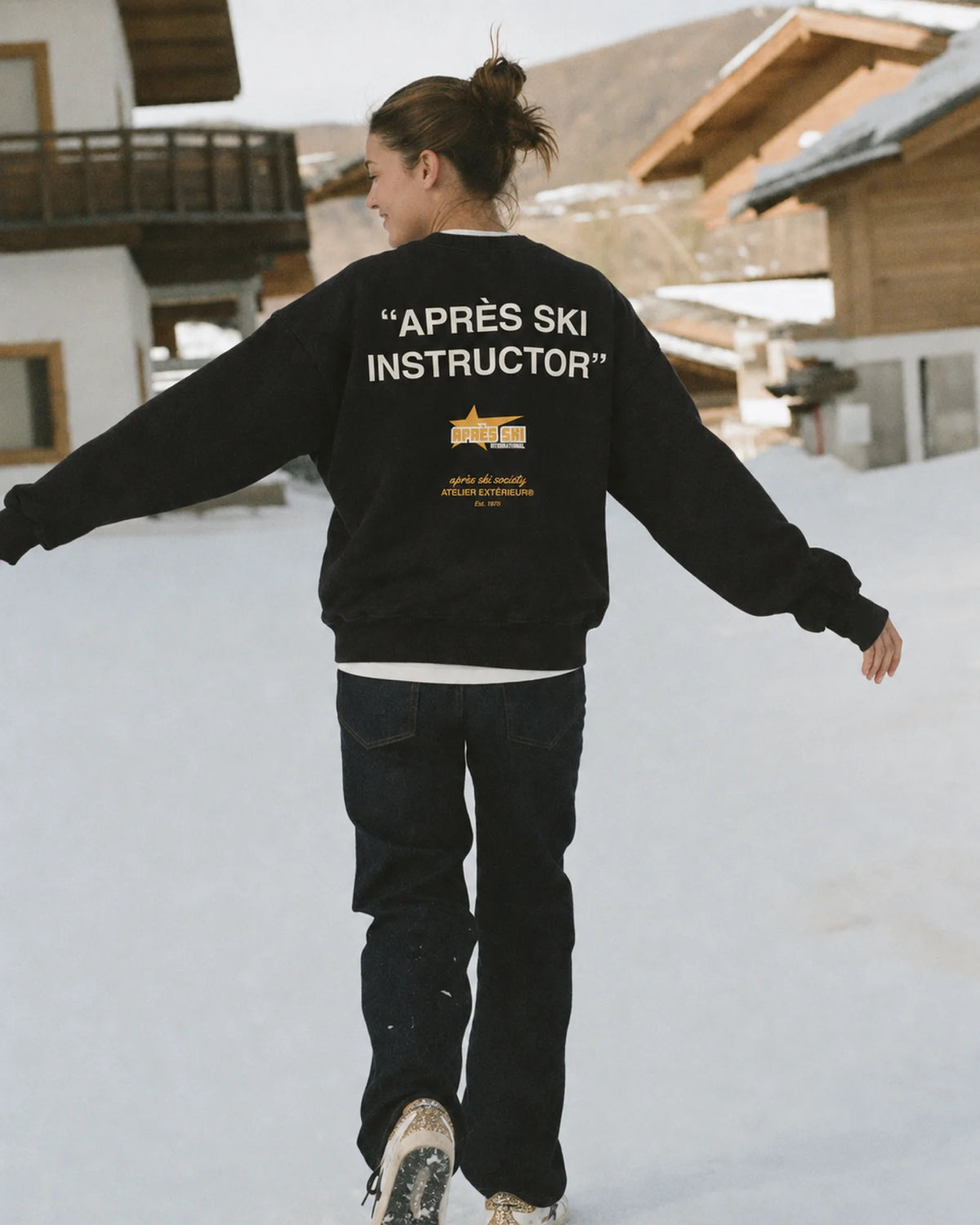 Woman wearing the Après Ski Instructor Crewneck in black, on location