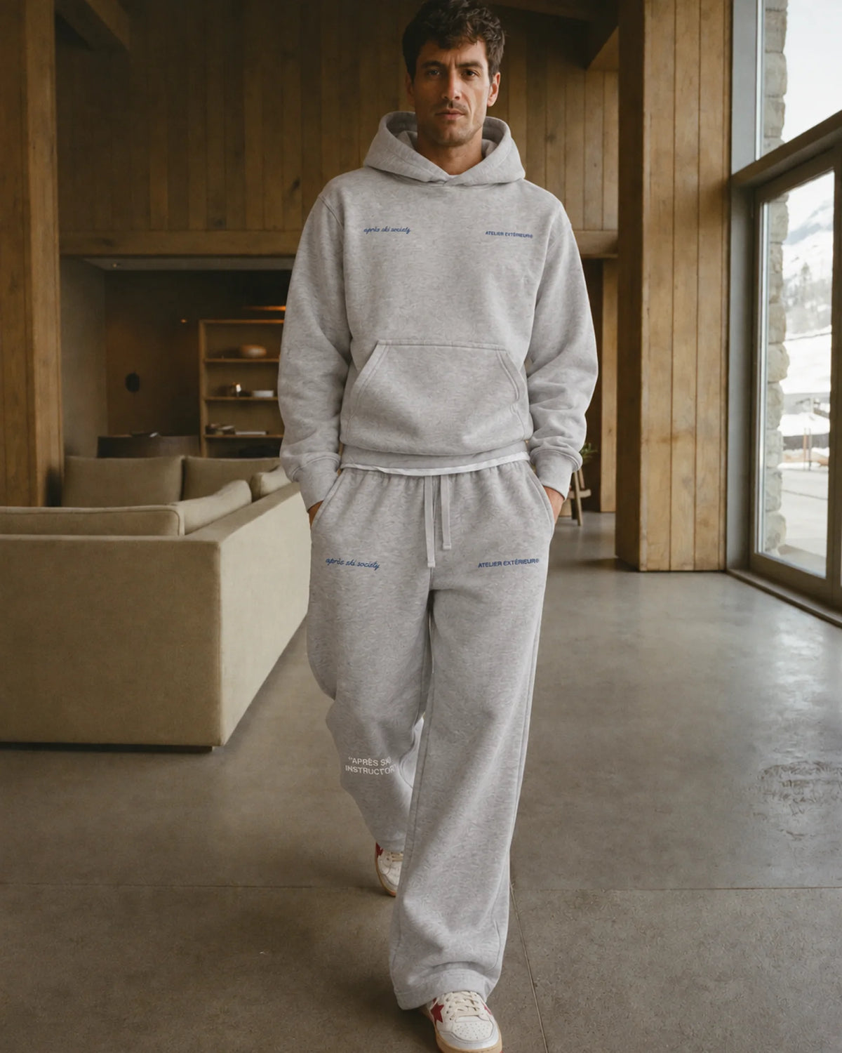 Man wearing the Après Ski Instructor Sweatpants - Straight Leg in heather gray with the Après Ski Instructor Hoodie in heather gray, on location