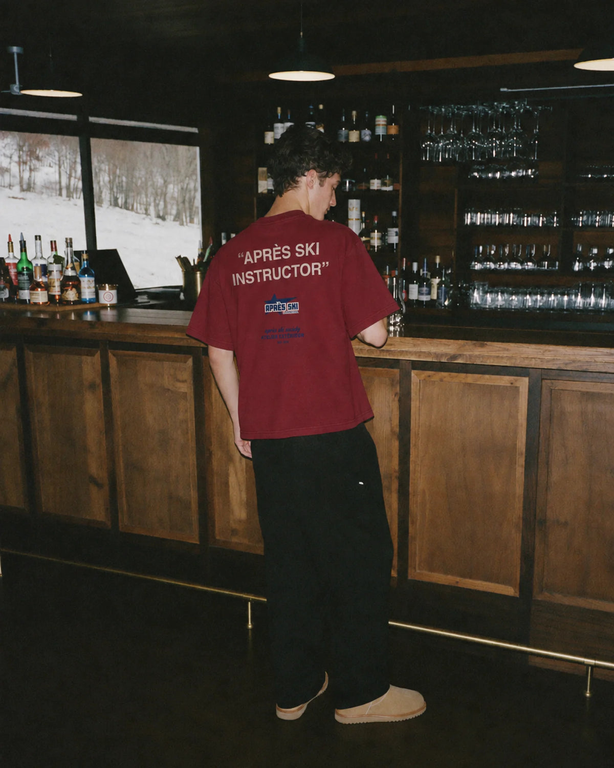 Man wearing the Après Ski Instructor Tee in red, on location