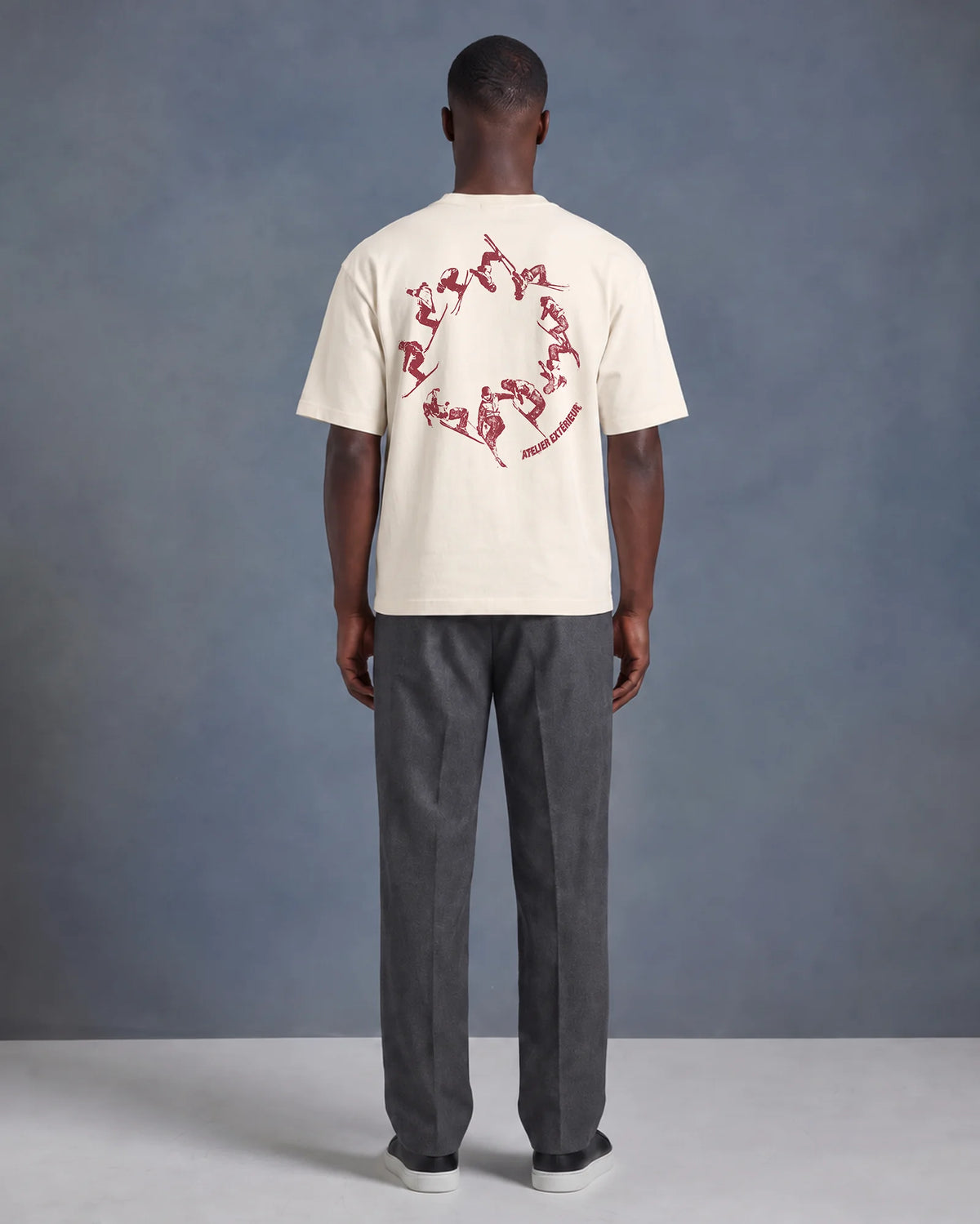 Model wearing the ecru Backflip tee in a studio, back view