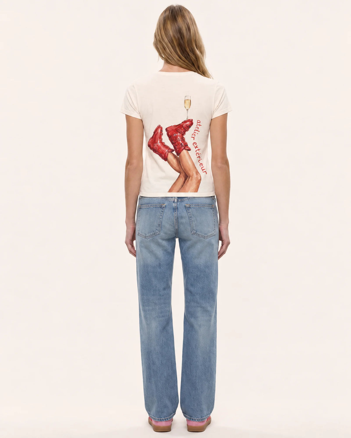 Model wearing the Champagne women's tee in ecru, back view, showing the ski boot and champagne print
