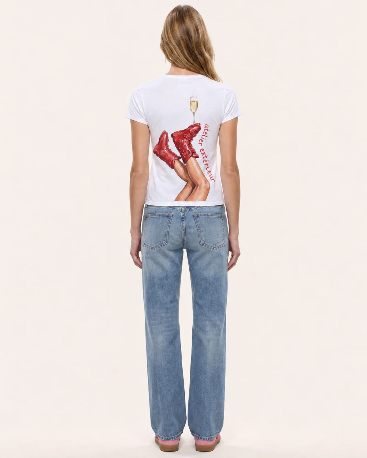 Model wearing the Champagne women's tee in white, back view, showing the ski boot and champagne print