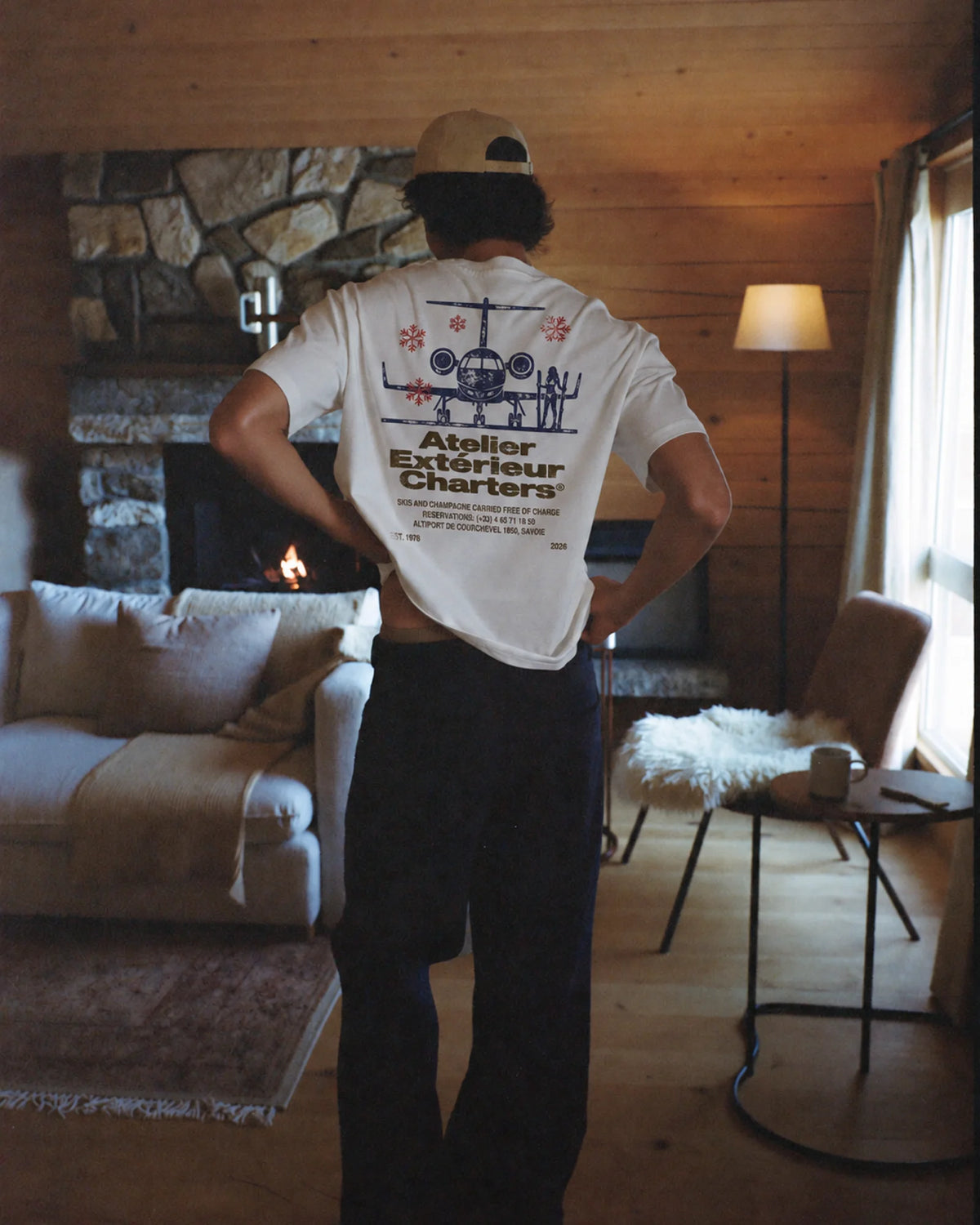 Man wearing the white Charters tee outdoors, showing the jet back print