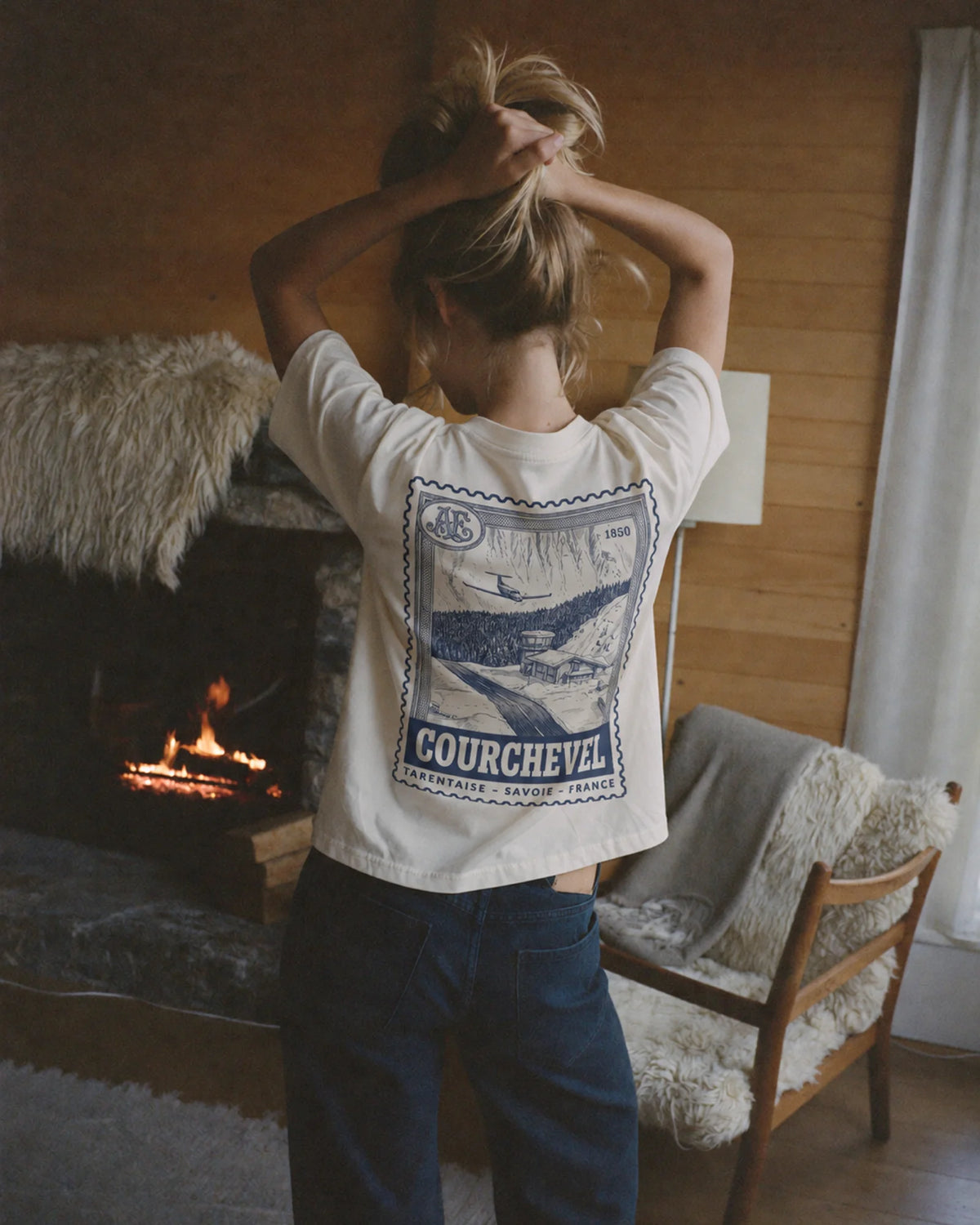 Woman wearing the ecru Courchevel tee outdoors, showing the resort stamp back print