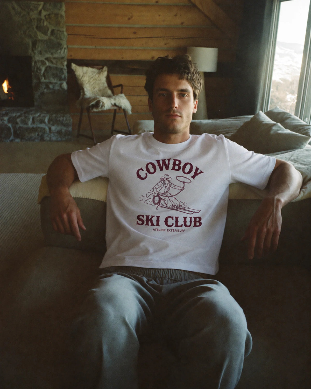 Man wearing the white Cowboy Ski Club tee outdoors, front view