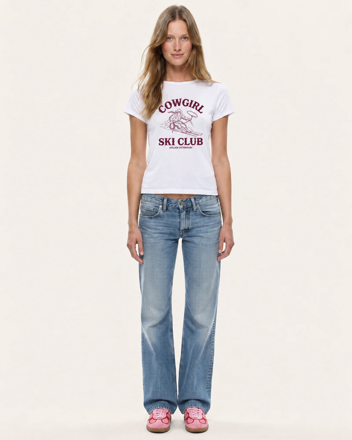 Model wearing the Cowgirl Ski Club women's tee in white with straight-leg jeans, front view