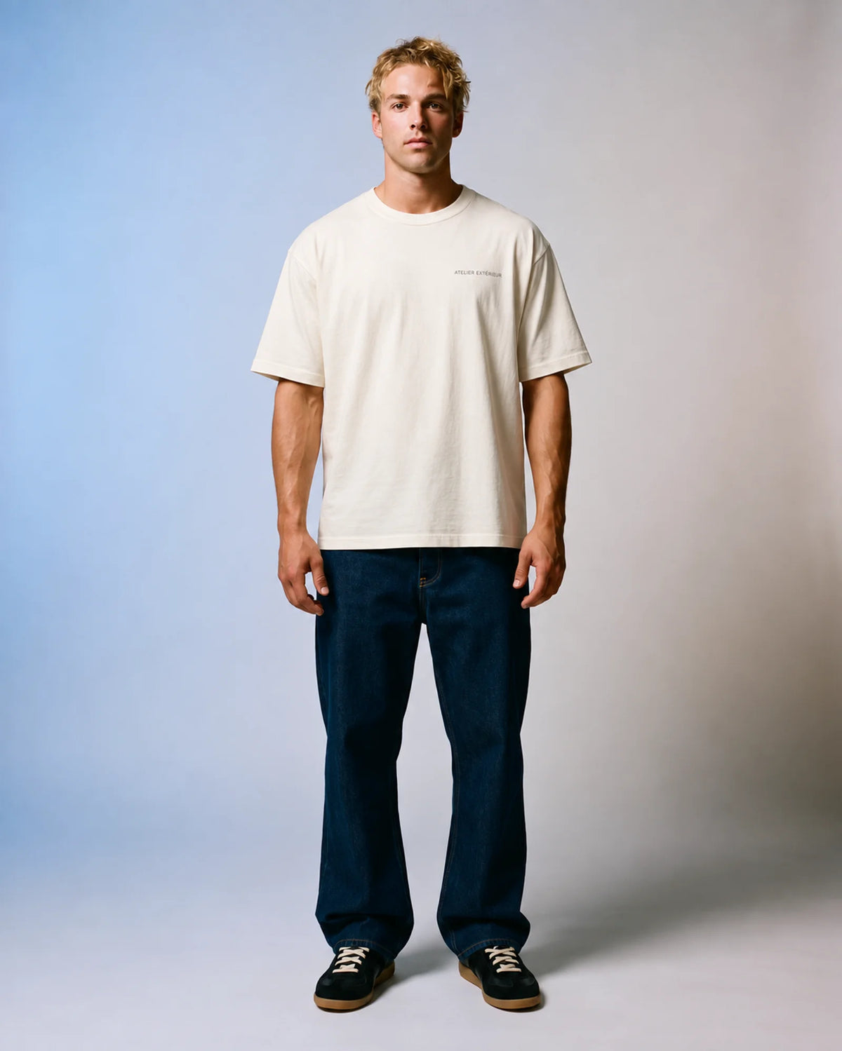 Model wearing the ecru Essentials tee in a studio, front view