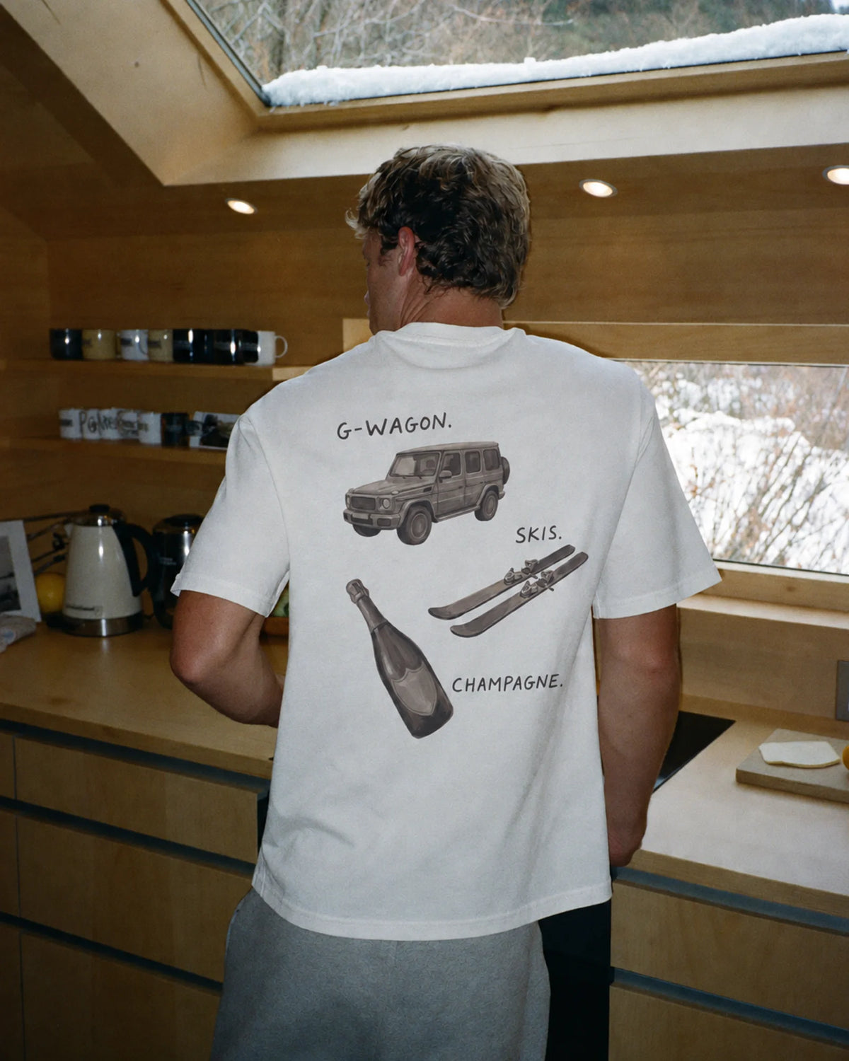 Man wearing the white Essentials tee outdoors, showing the hand-painted back print