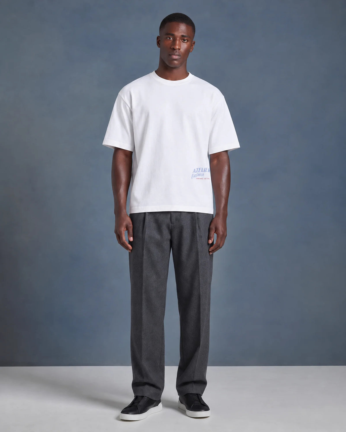 Model wearing the white Heli Skiing tee in a studio, front view