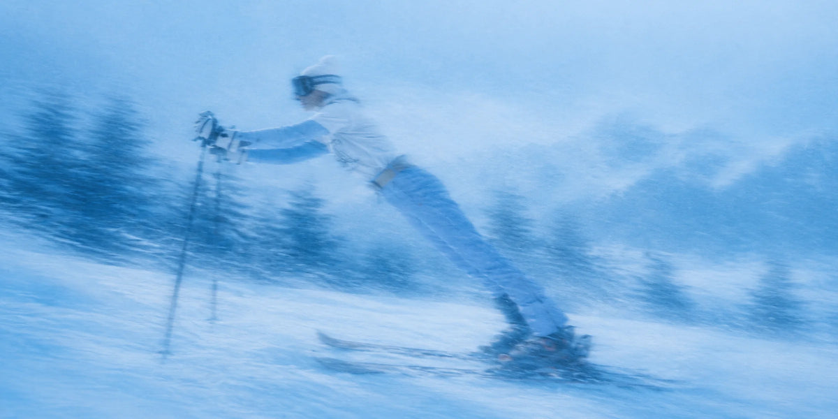 Woman skiing fast through snow-covered pines