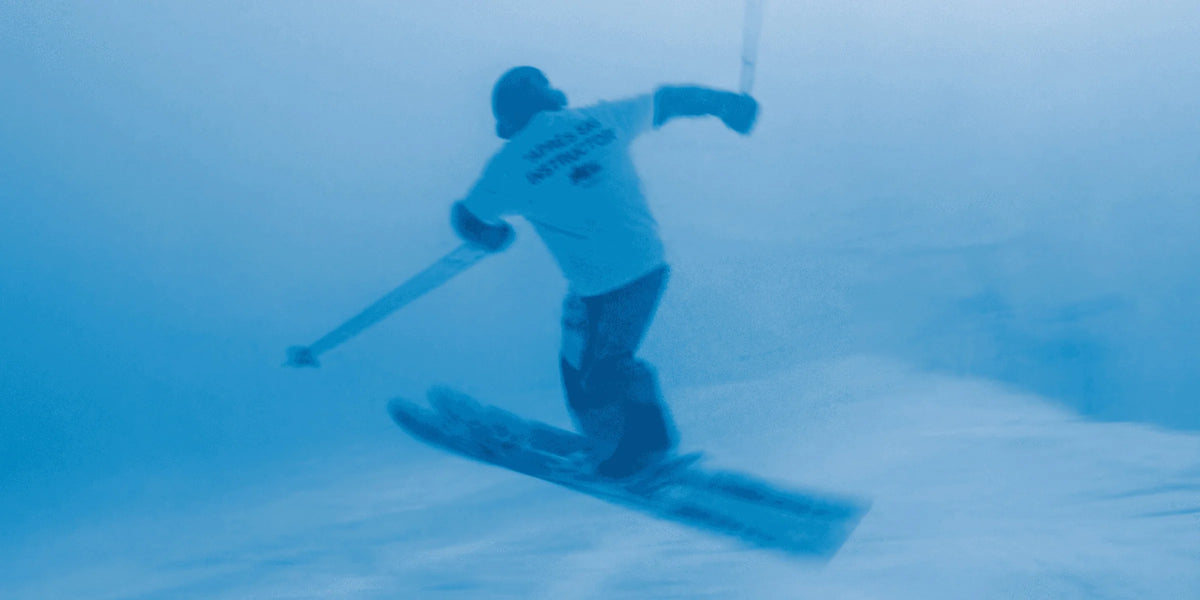 Skier in an Après Ski Instructor tee carving through fresh snow