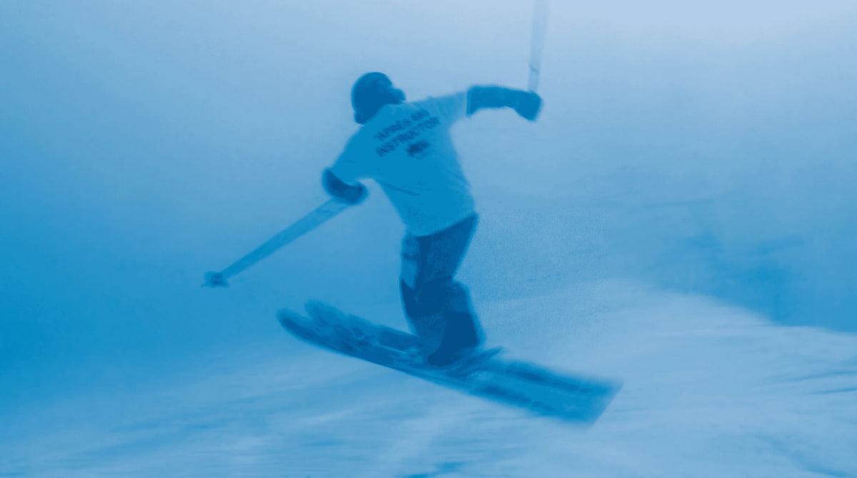 Skier in an Après Ski Instructor tee carving through fresh snow