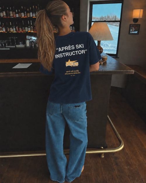 Woman wearing the navy Après Ski Instructor tee, back print