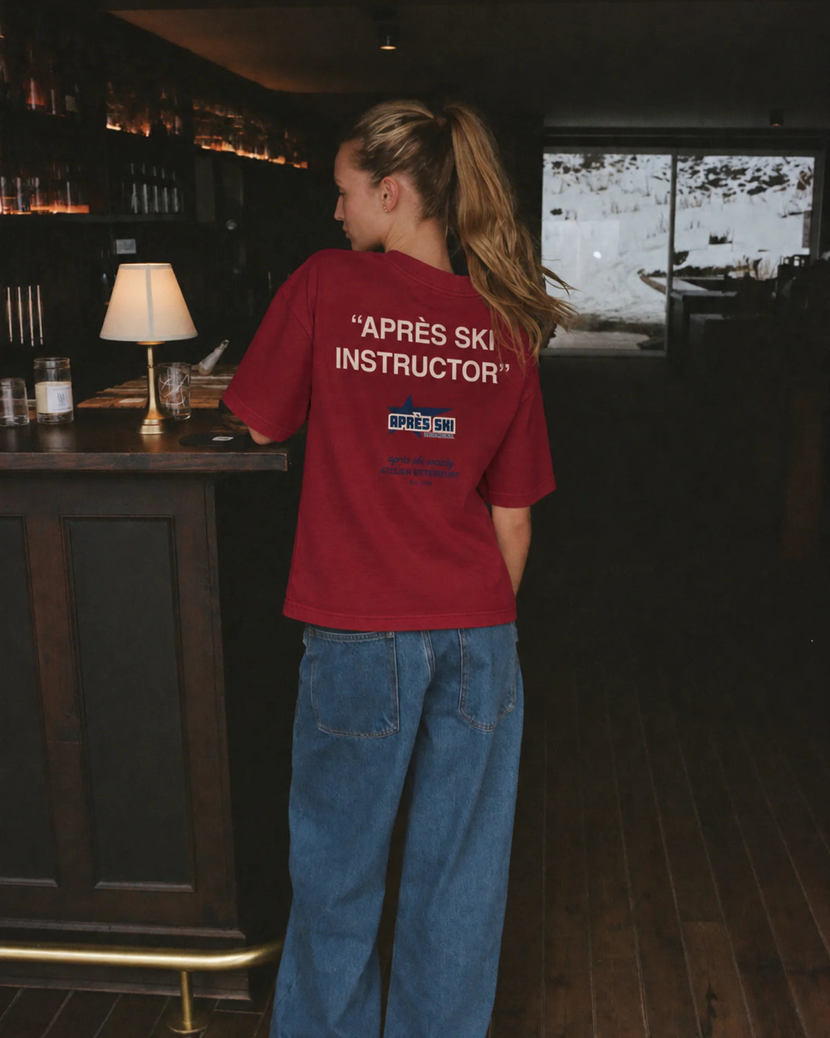 Woman wearing the red Après Ski Instructor tee, back print