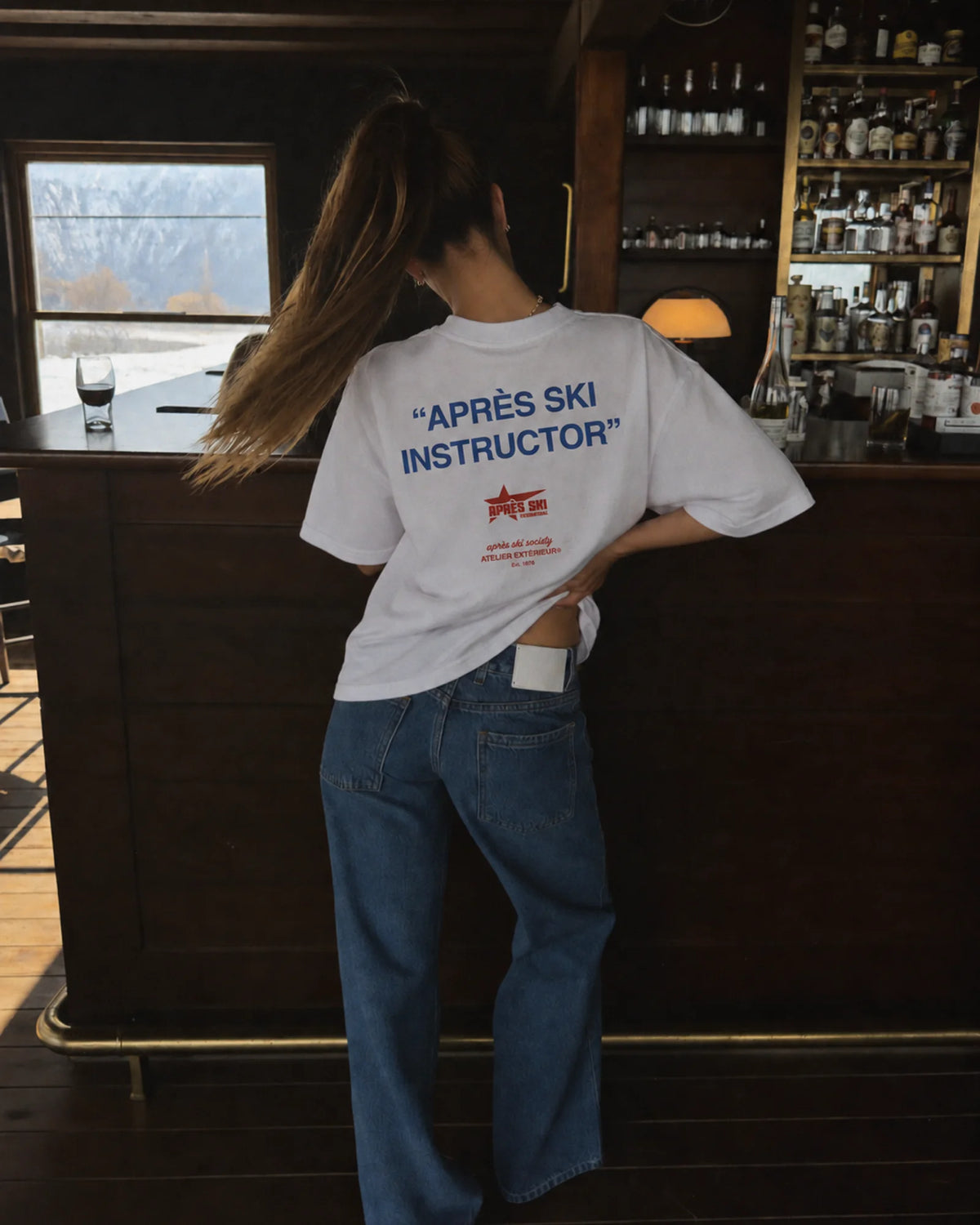 Woman wearing the white Après Ski Instructor tee, back print