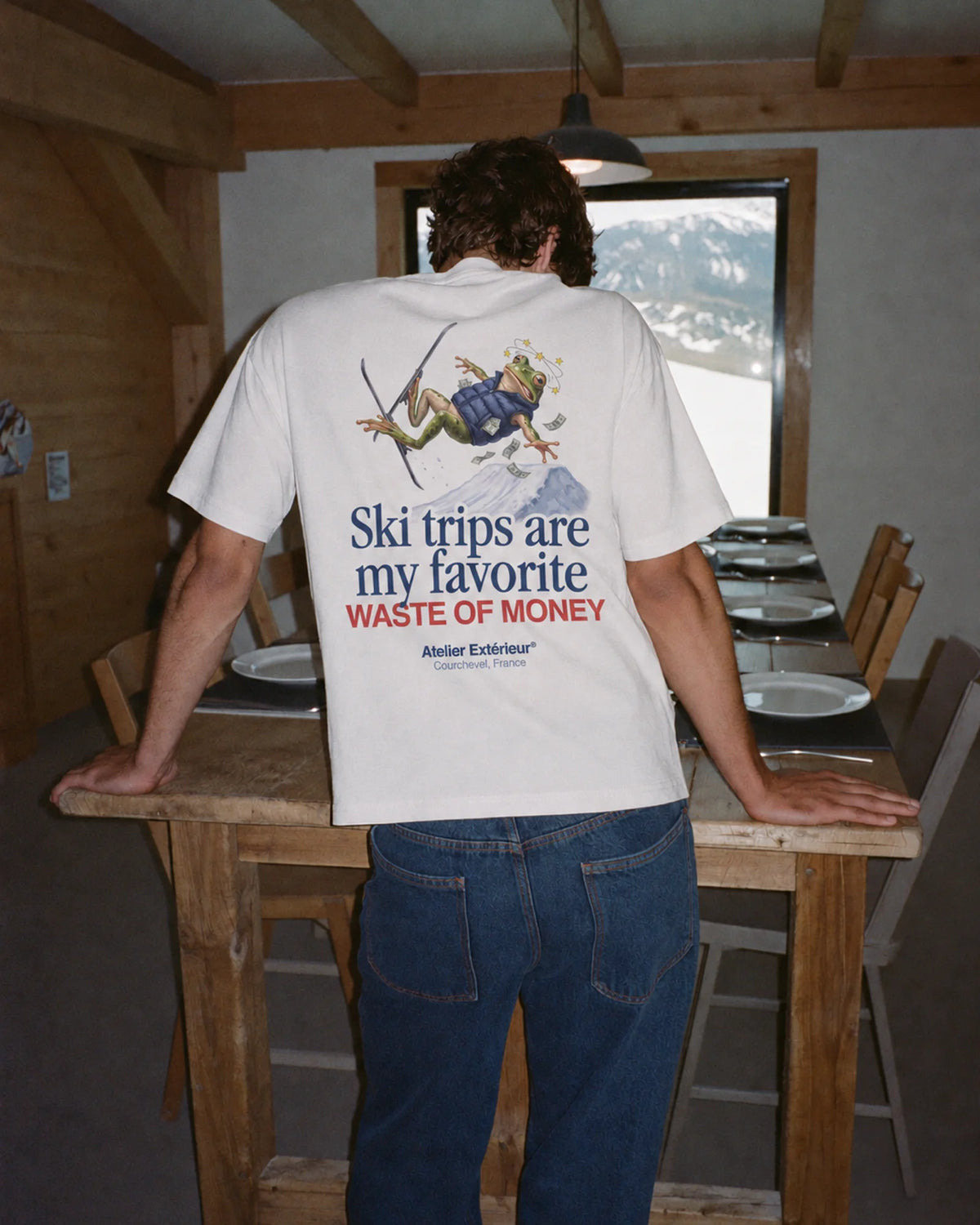 Man wearing the white Money tee outdoors, showing the slogan back print