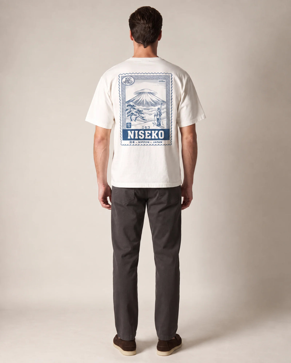 Model wearing the white Niseko tee in a studio, back view