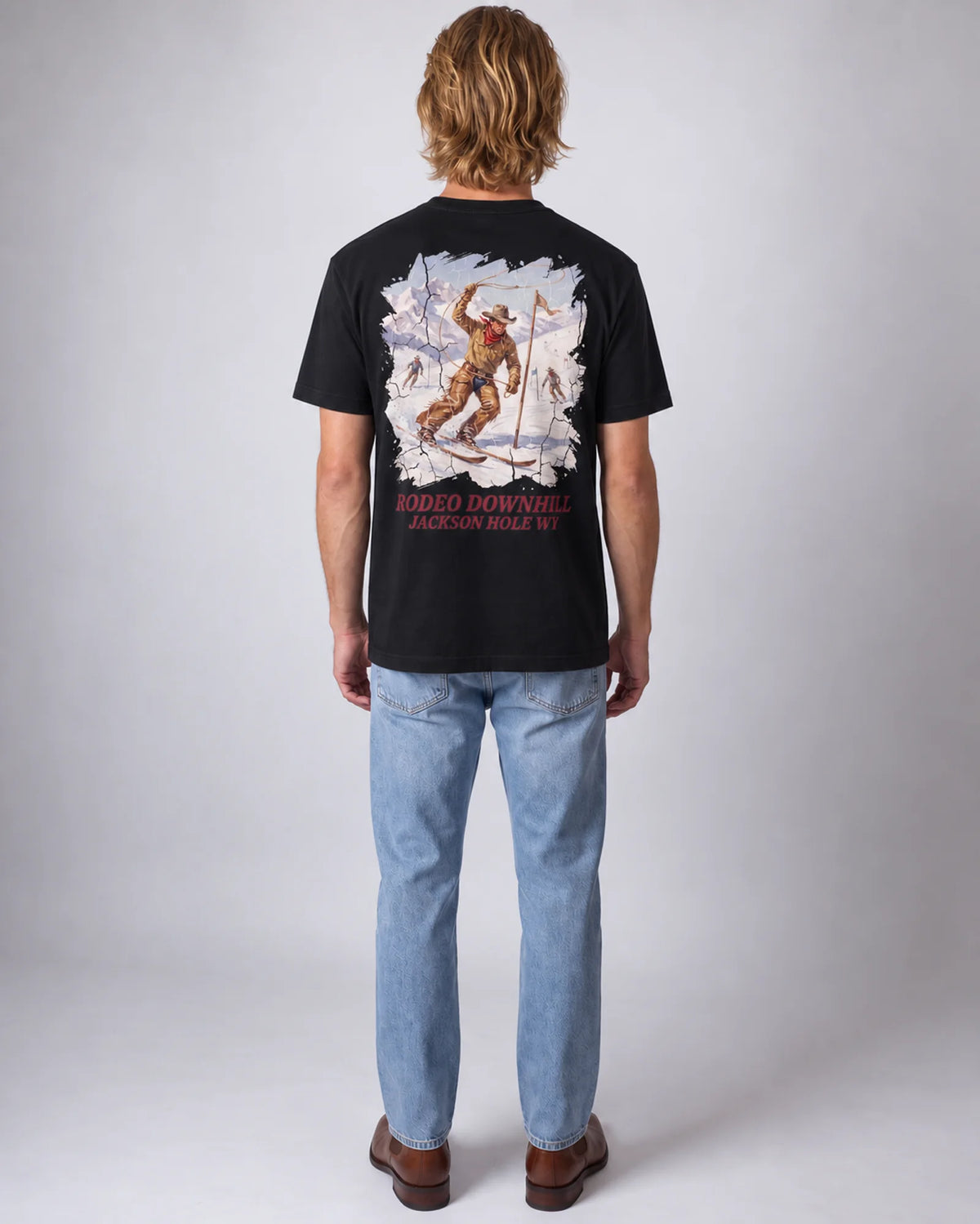 Model wearing the black Rodeo Downhill tee in a studio, back view