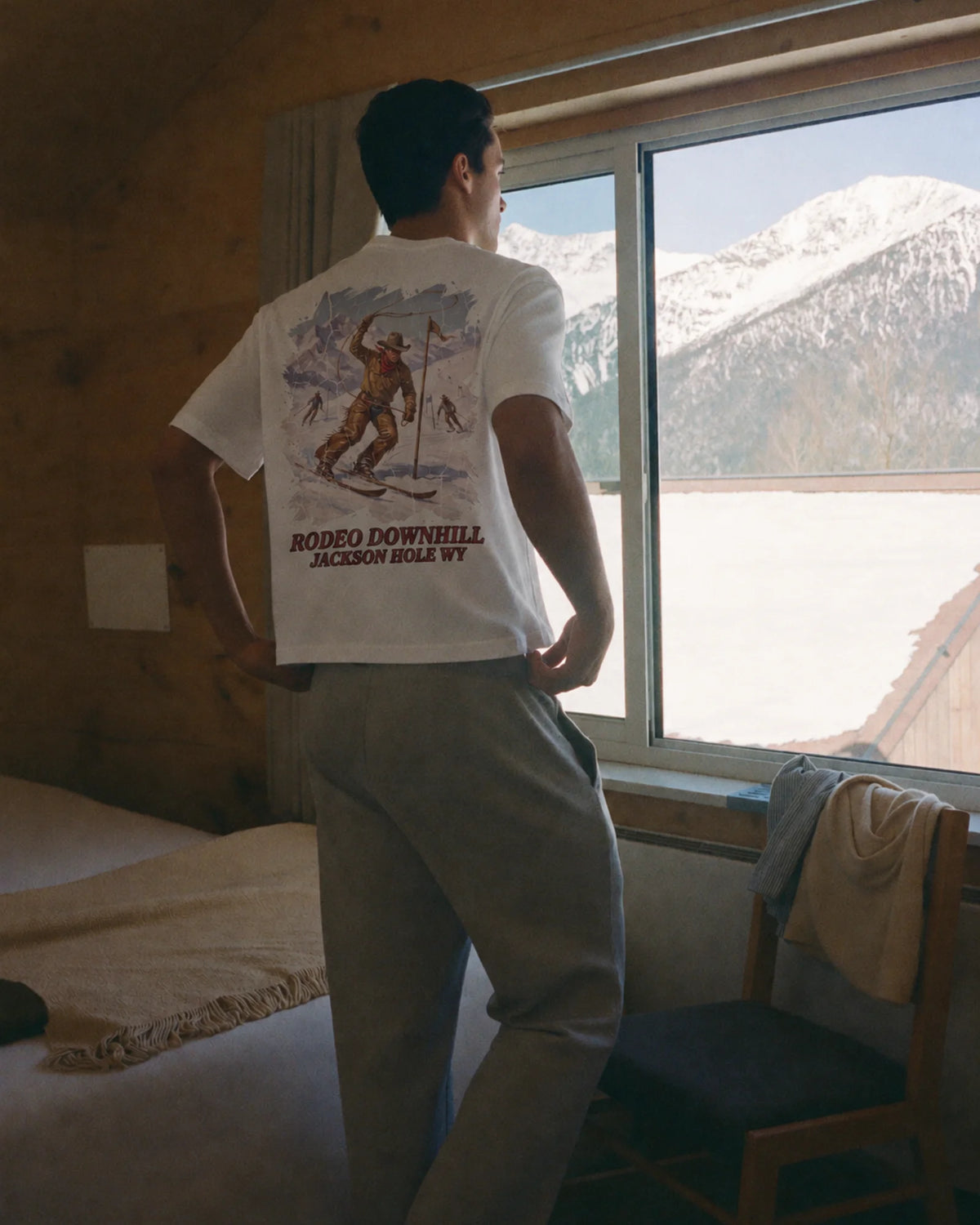 Man wearing the white Rodeo Downhill tee outdoors, showing the back print