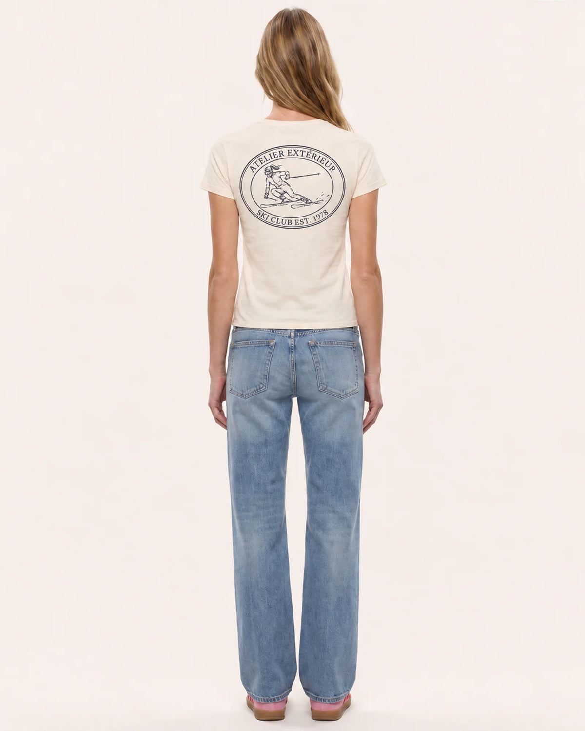 Model wearing the Ski Club women's tee in ecru, back view, showing the oval emblem