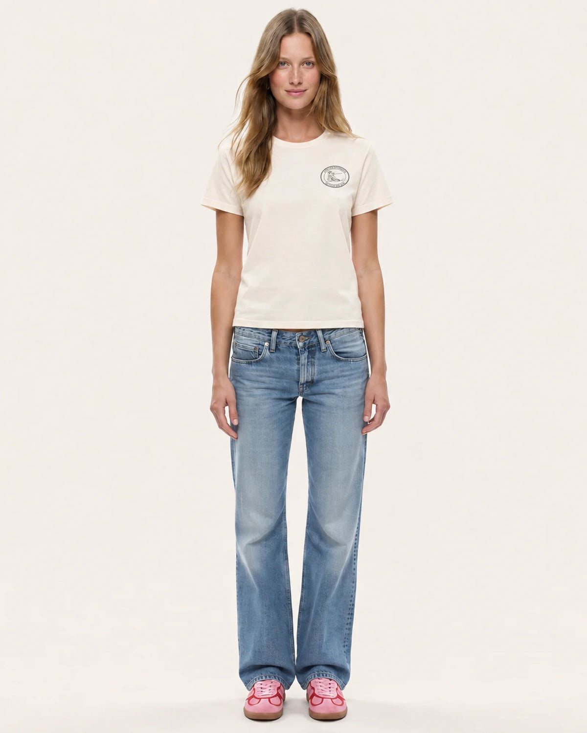 Model wearing the Ski Club women's tee in ecru with straight-leg jeans, front view