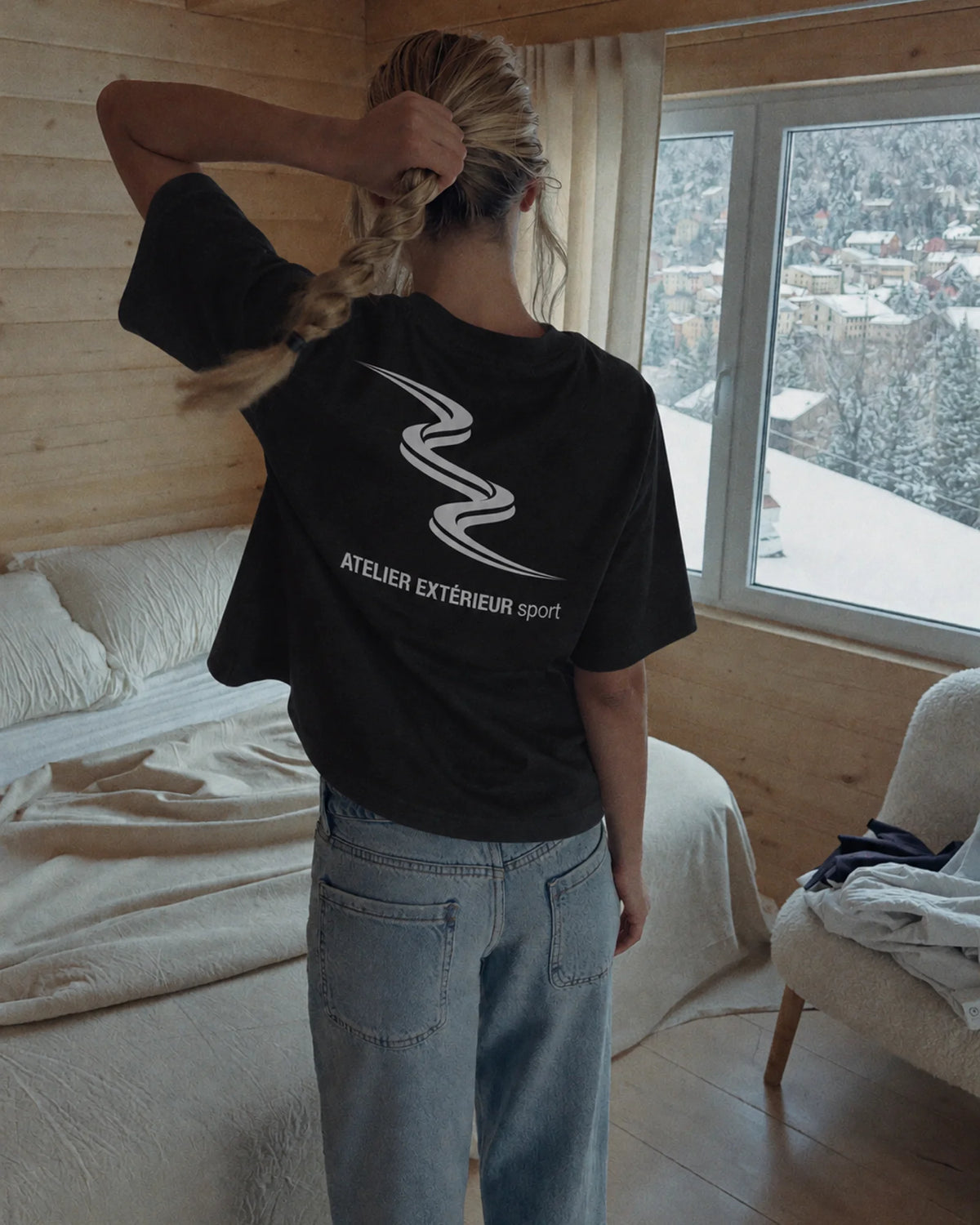 Woman wearing the black Sport tee in the snow, back print visible