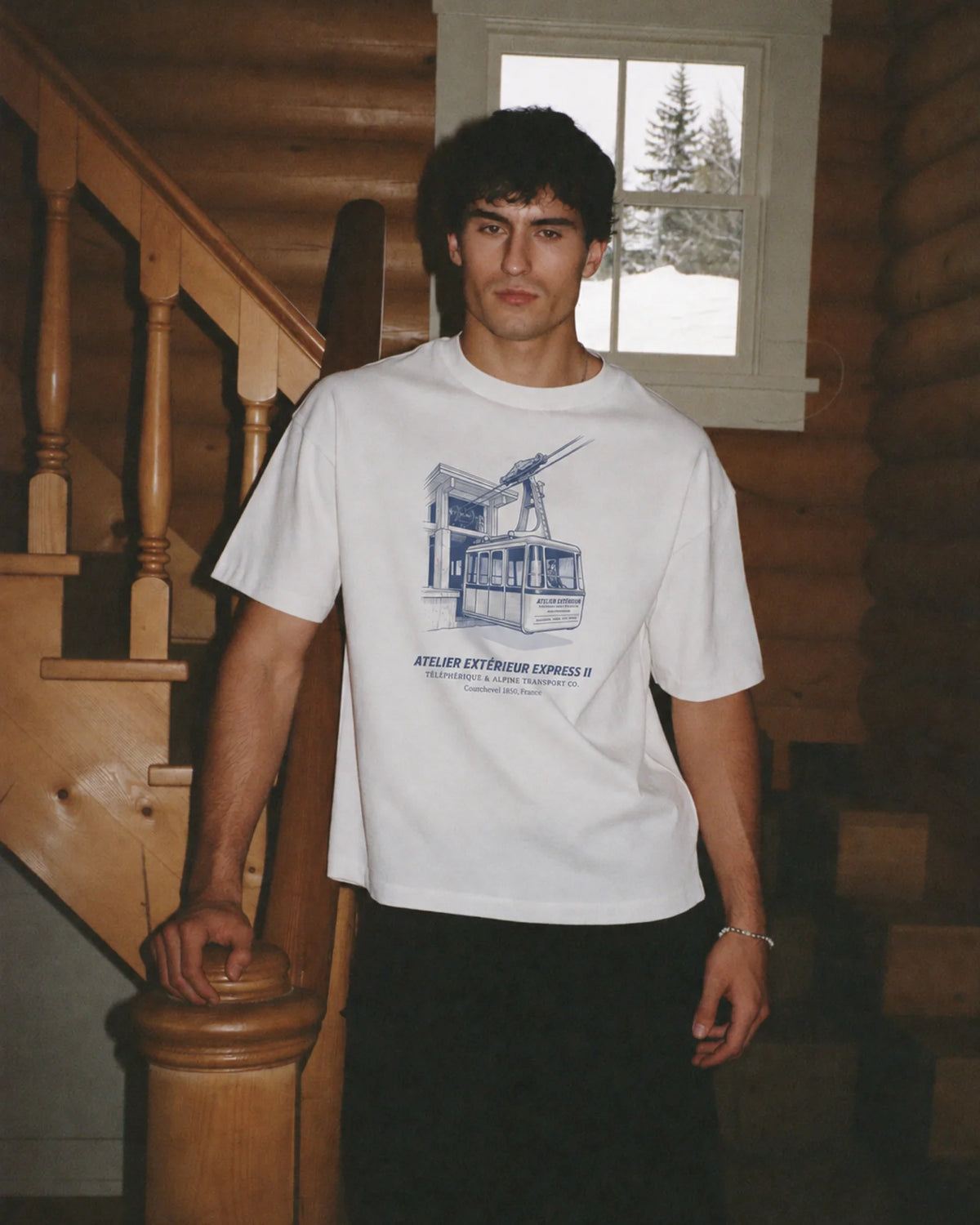 Man wearing the white Télécabine tee in the snow, front print visible
